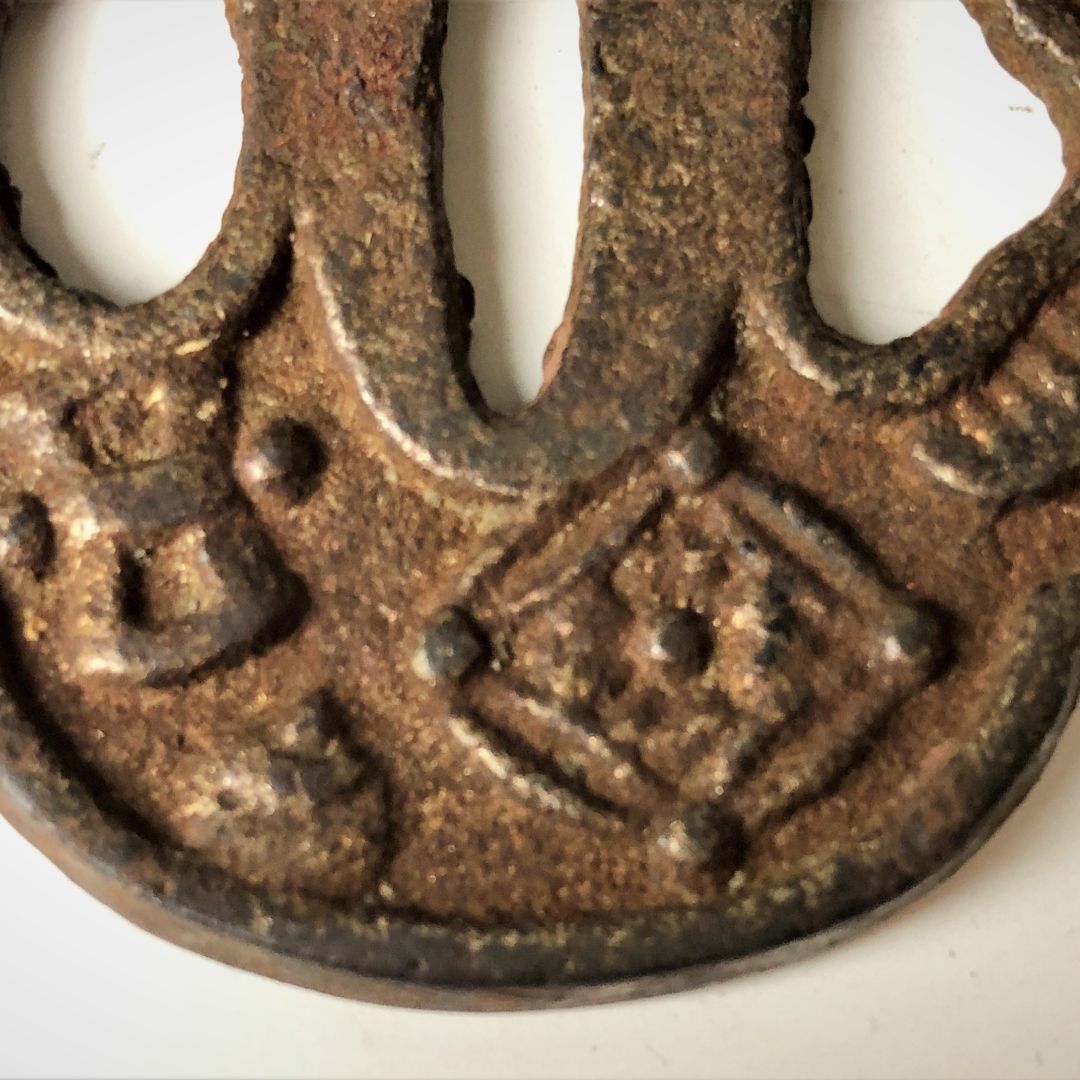 Rust-colored metal object with intricate design on a white background