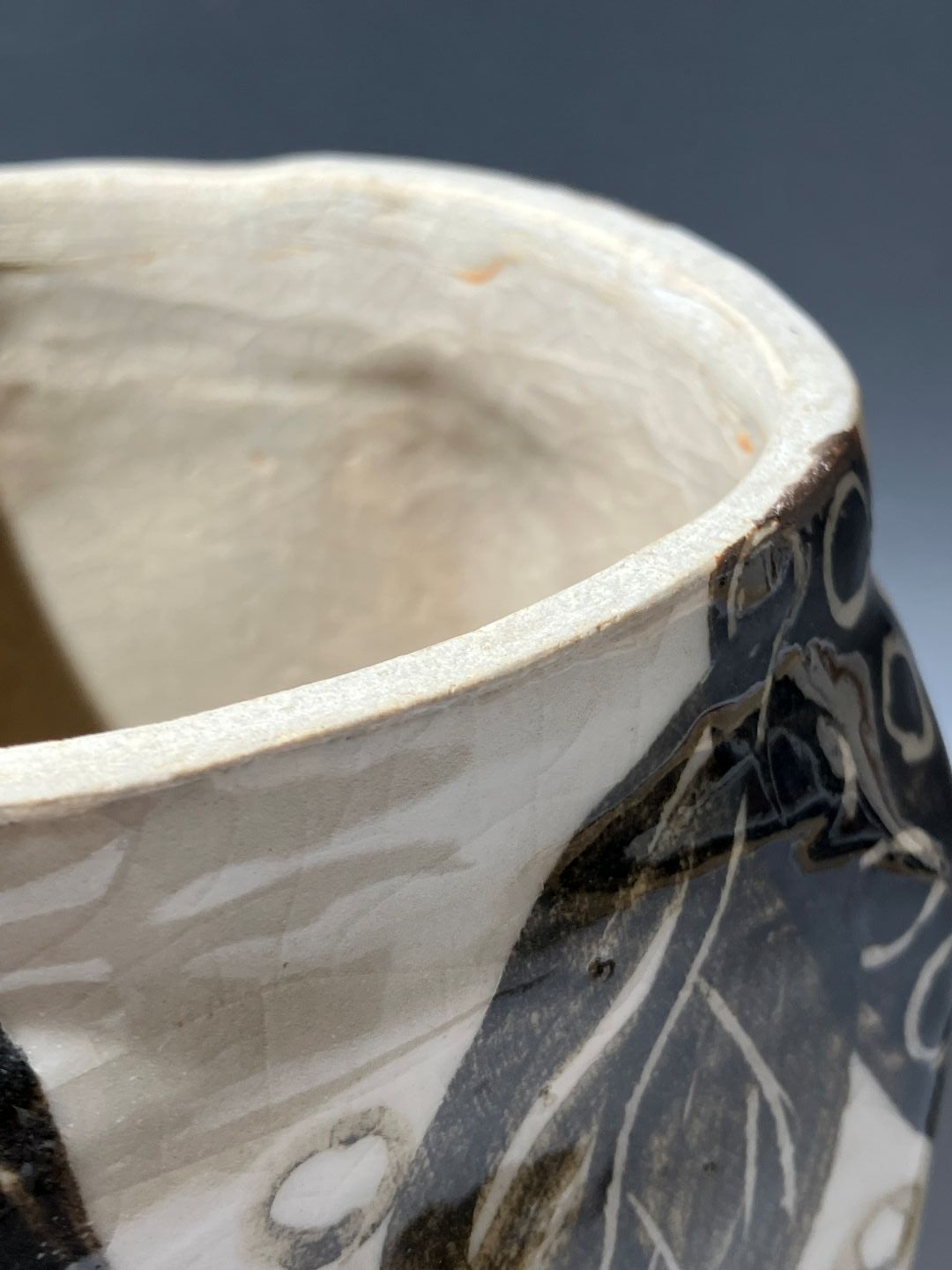 Close-up of a ceramic bowl with black and white patterns on a gray background