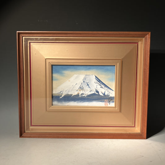Framed artwork of a mountain landscape with a gold frame.