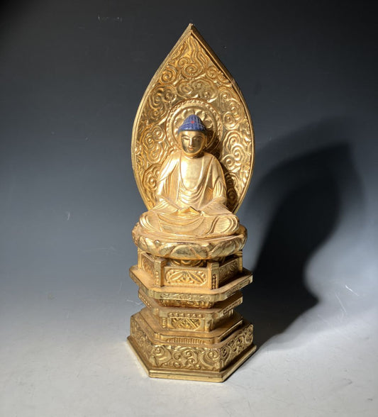 Gold Buddha statue with intricate design on a dark background