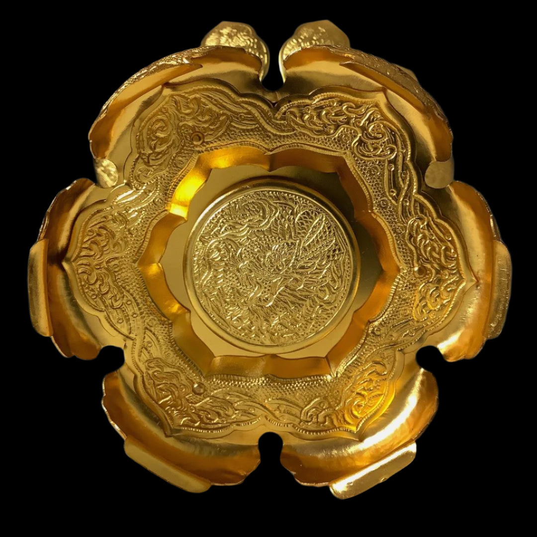 A close-up of the ornate golden base of a Japanese lantern, displaying intricate floral embossing and scalloped edges, against a soft-lit background.