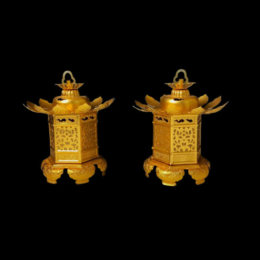 A pair of ornate golden Japanese lanterns with intricate cut-out designs and stylized bird wing accents, displayed on matching bases against a dark gray background.
