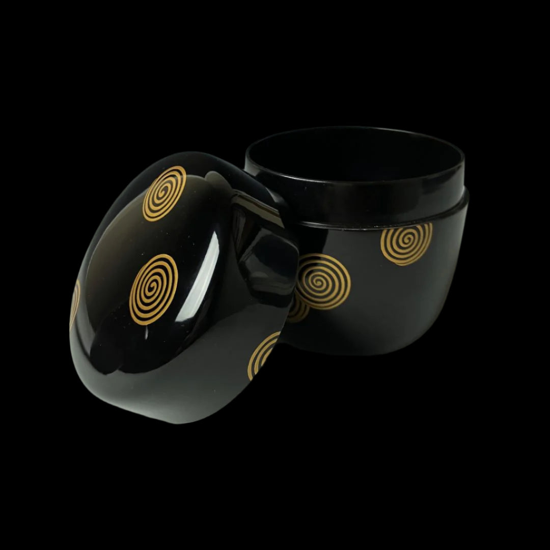 An open 19th-century Japanese lacquered makie natsume tea caddy, displaying its black finish adorned with gold spiral designs, highlighting the intricate craftsmanship and elegance of traditional Japanese tea ware.