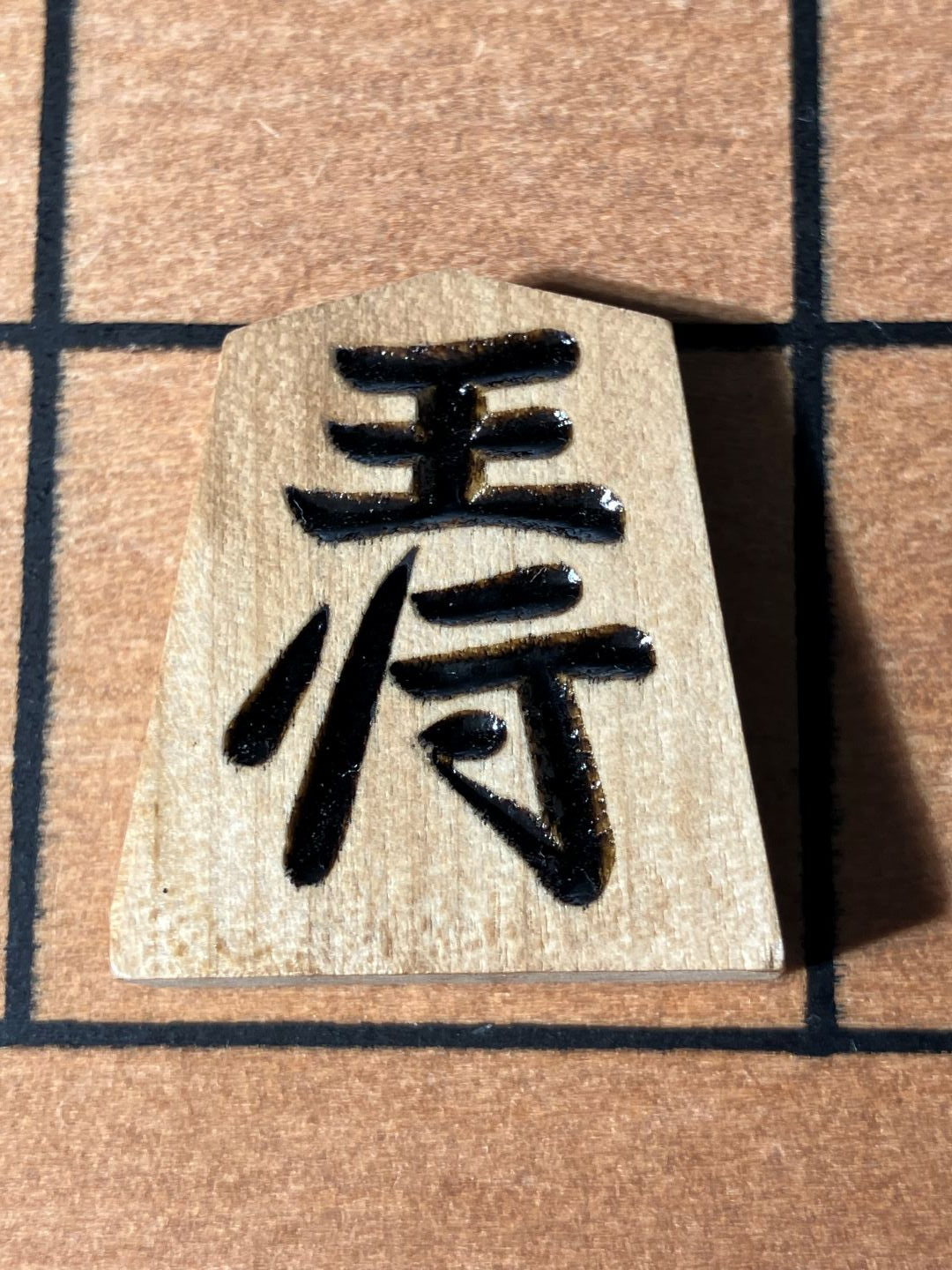 Black calligraphy on a beige card with a grid background