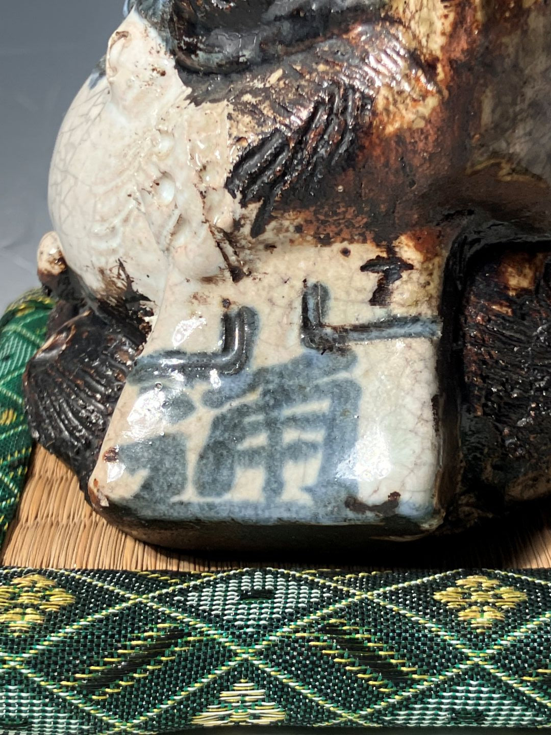 Close-up of a ceramic object with engraved characters on a textured green fabric background