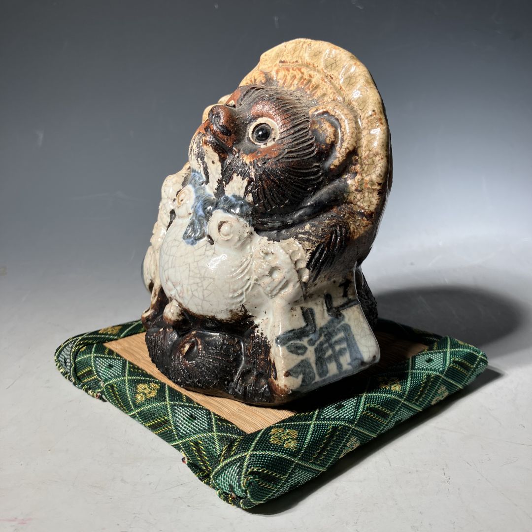 Ceramic owl figurine on a green checkered cloth with a gray background