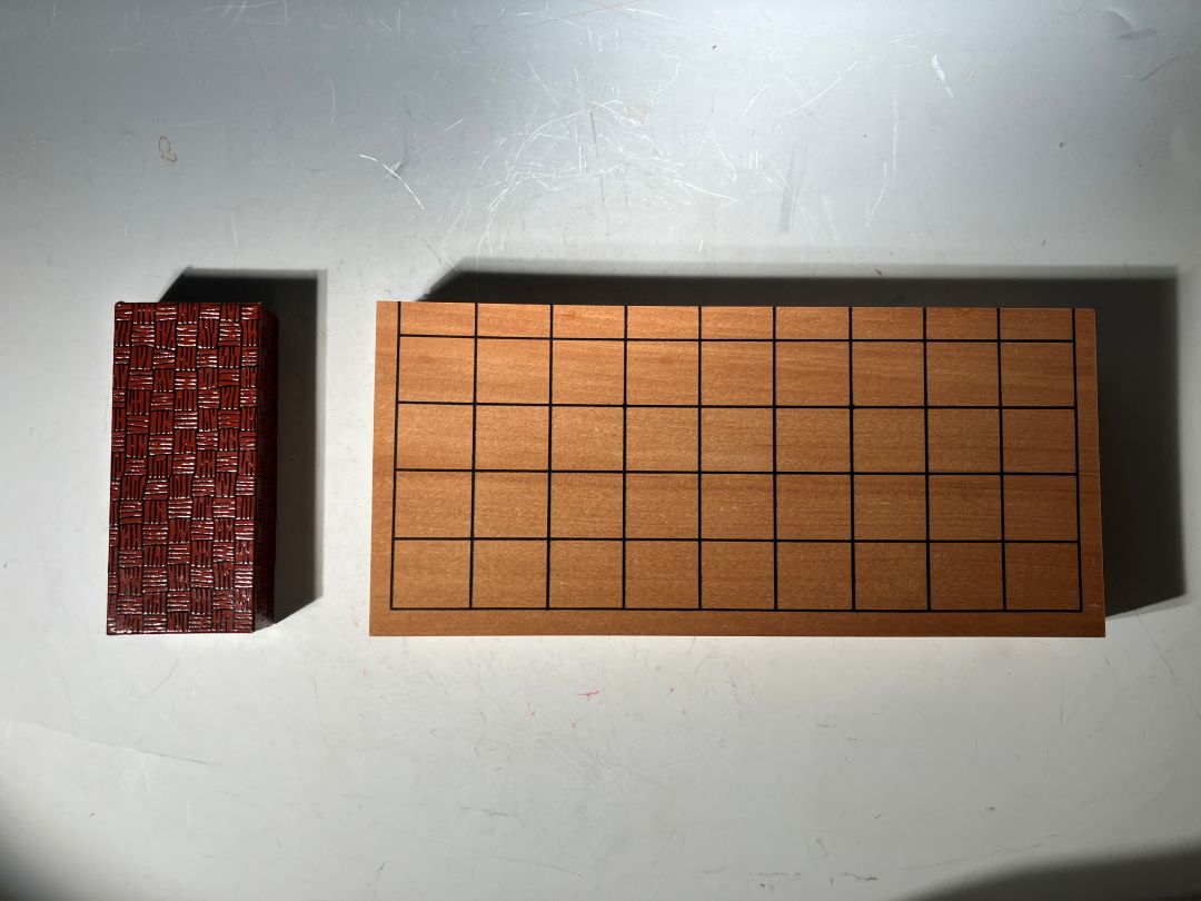 Wooden shogi board with red corner piece on a white background