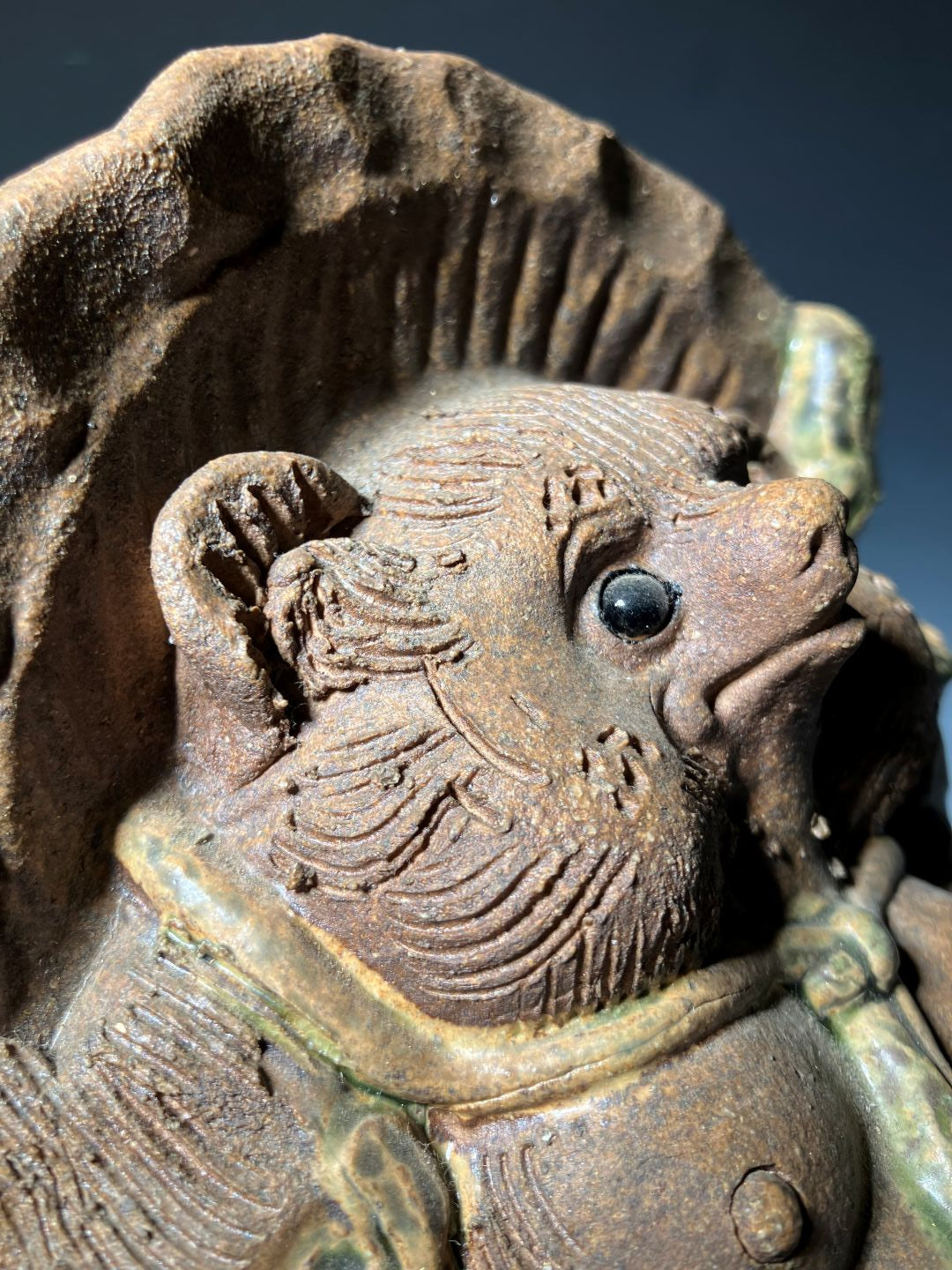 Close-up of a ceramic turtle with detailed carvings on a dark background