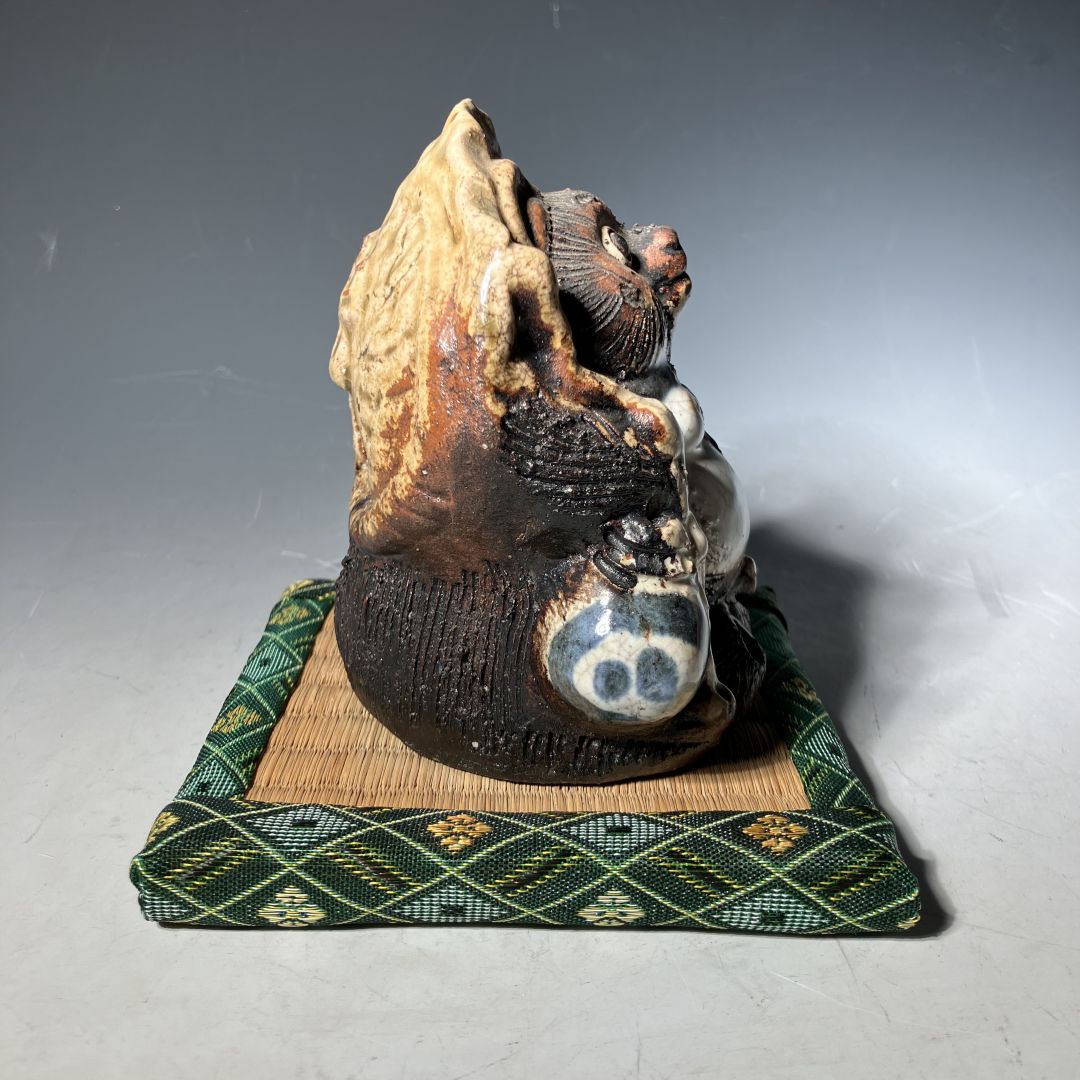 Ceramic sculpture of a wolf on a woven mat with a plain background