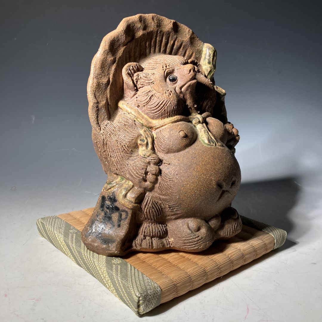 Ceramic figure of a mythical creature on a wooden stand with a gray background