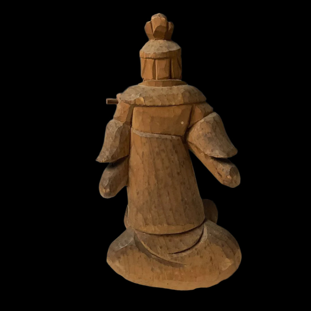 A rear view of a wooden sculpture of Komokuten, a Japanese Buddhist guardian deity, standing 14 cm tall, carved with a flowing robe and a traditional headdress, exhibiting detailed textures and natural wood grain.
