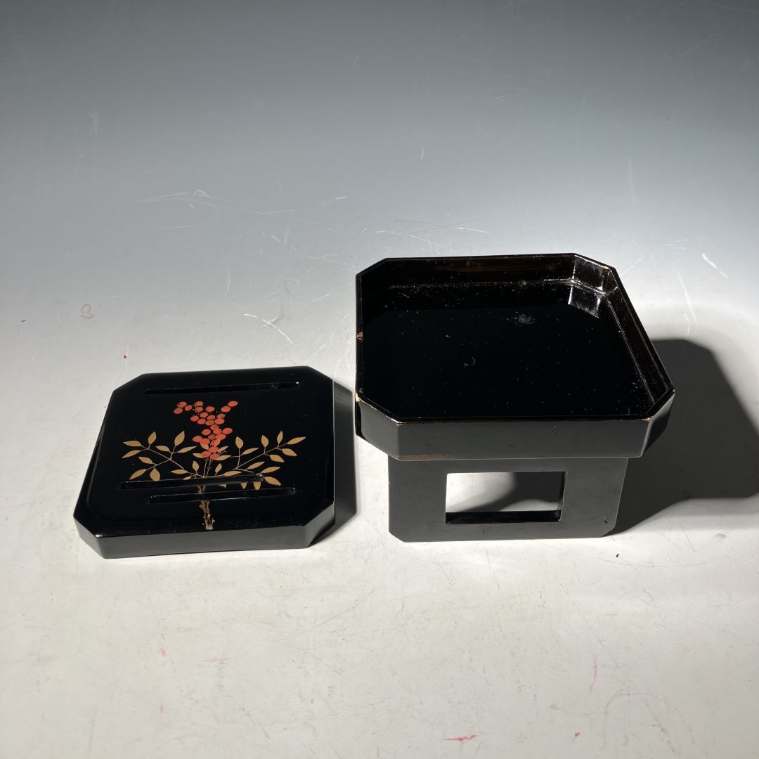 Black lacquerware box with floral design on a gray background