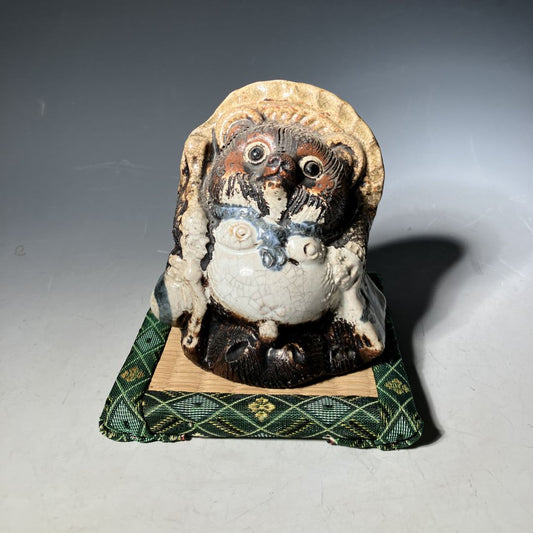 Ceramic owl figurine on a green fabric base against a gray background