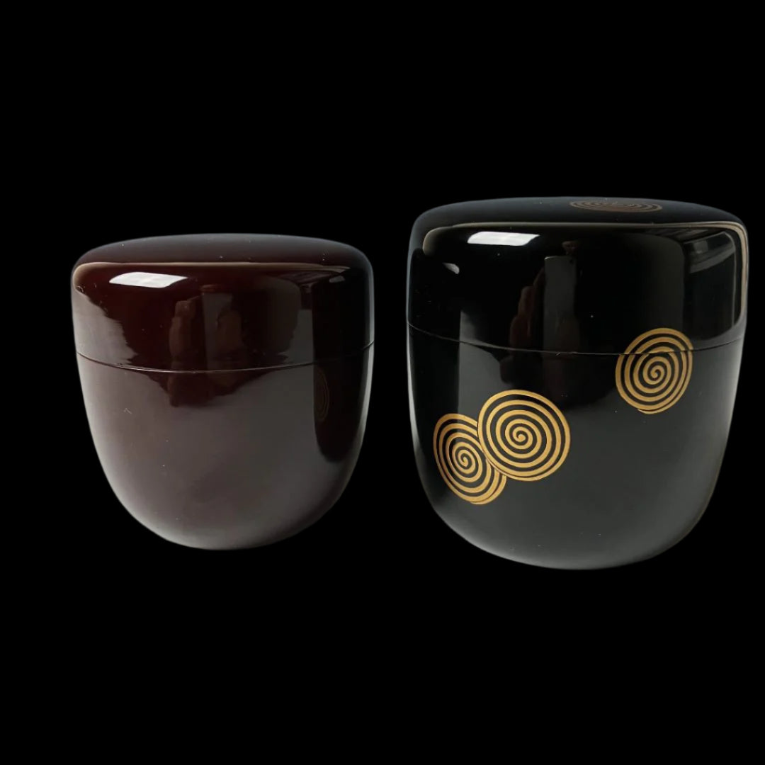 Two 19th-century Japanese lacquered makie natsume tea caddies in black and brown with gold floral designs, showcasing traditional craftsmanship and elegance.
