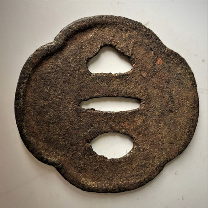 Rust-colored metal object with three circular holes on a white background