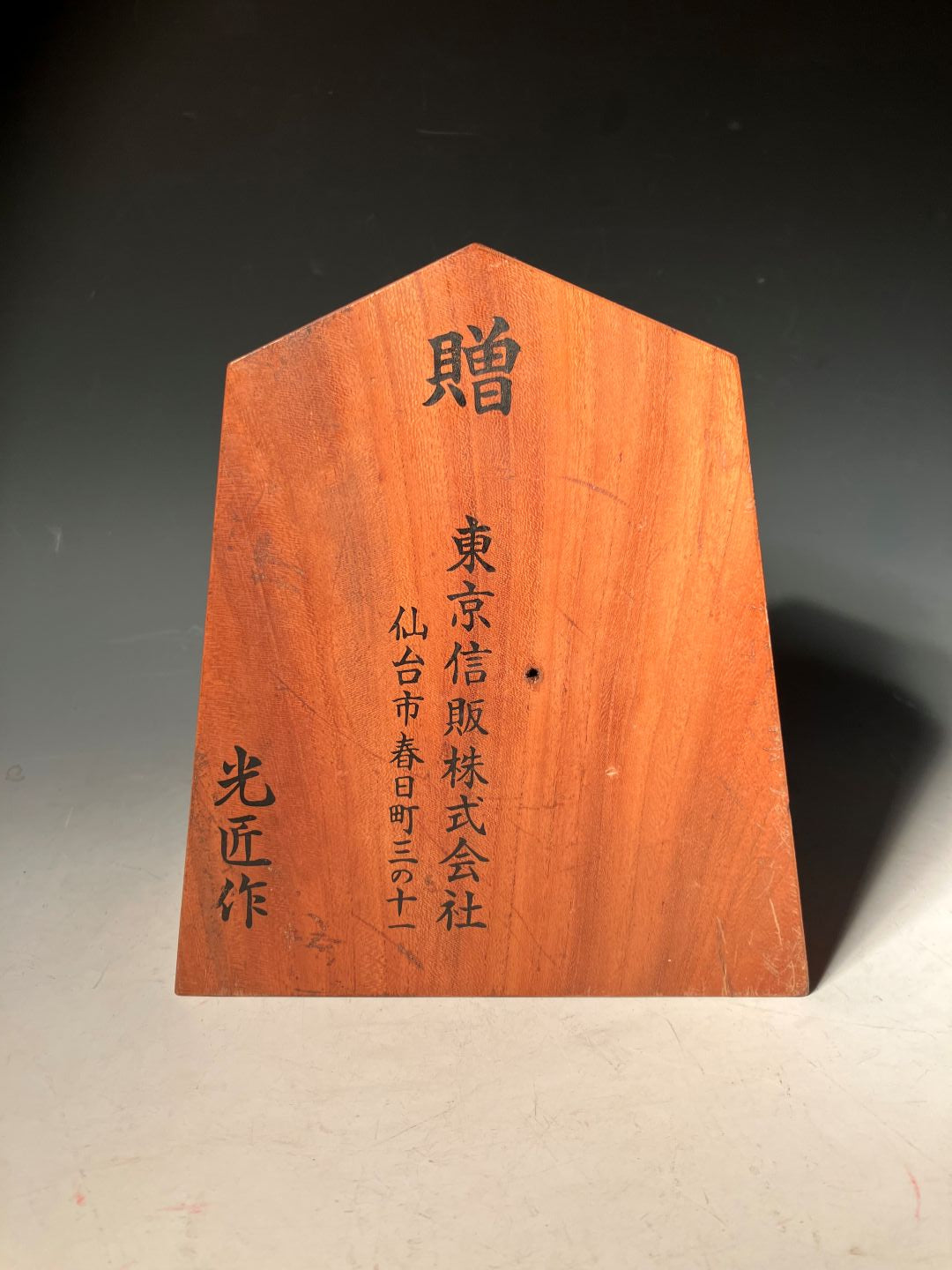 Wooden plaque with engraved text on a dark surface
