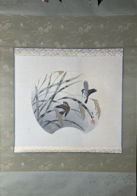 Framed artwork of a bird perched on a branch with leaves and flowers on a light gray background.