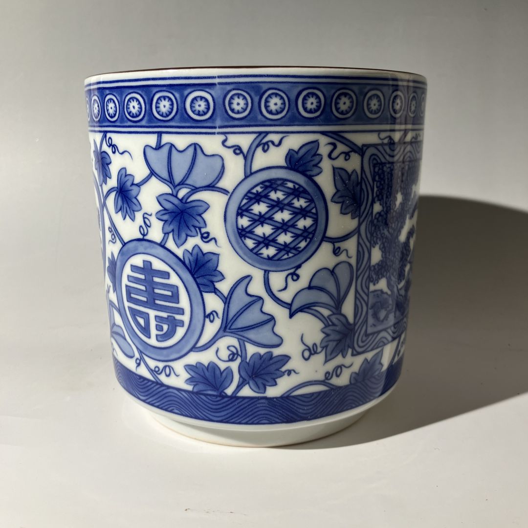 Blue and white ceramic cup with intricate patterns on a plain background