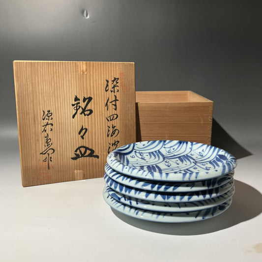 Set of blue and white ceramic plates with a wooden box in the background