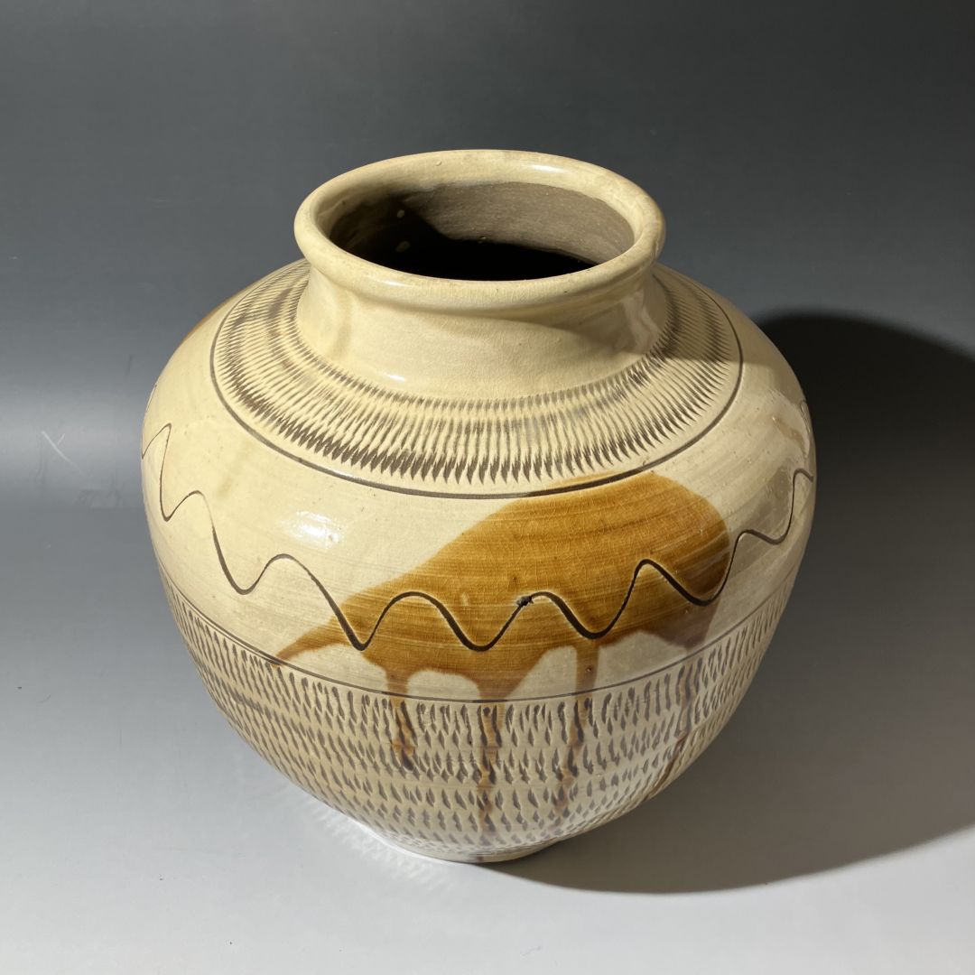 Ceramic jar with decorative patterns on a gray background