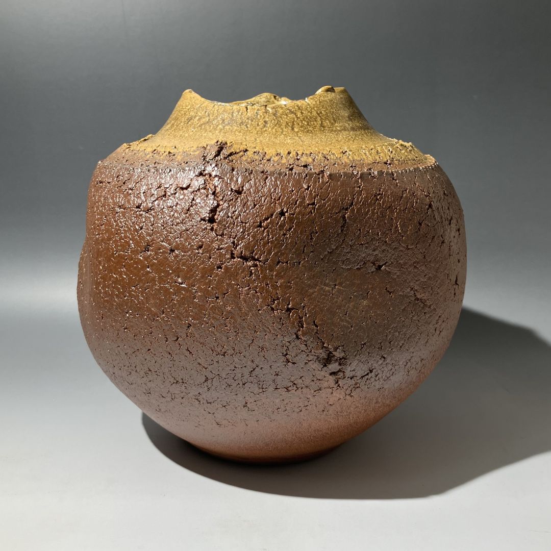 Brown ceramic vase with textured surface on a gray background