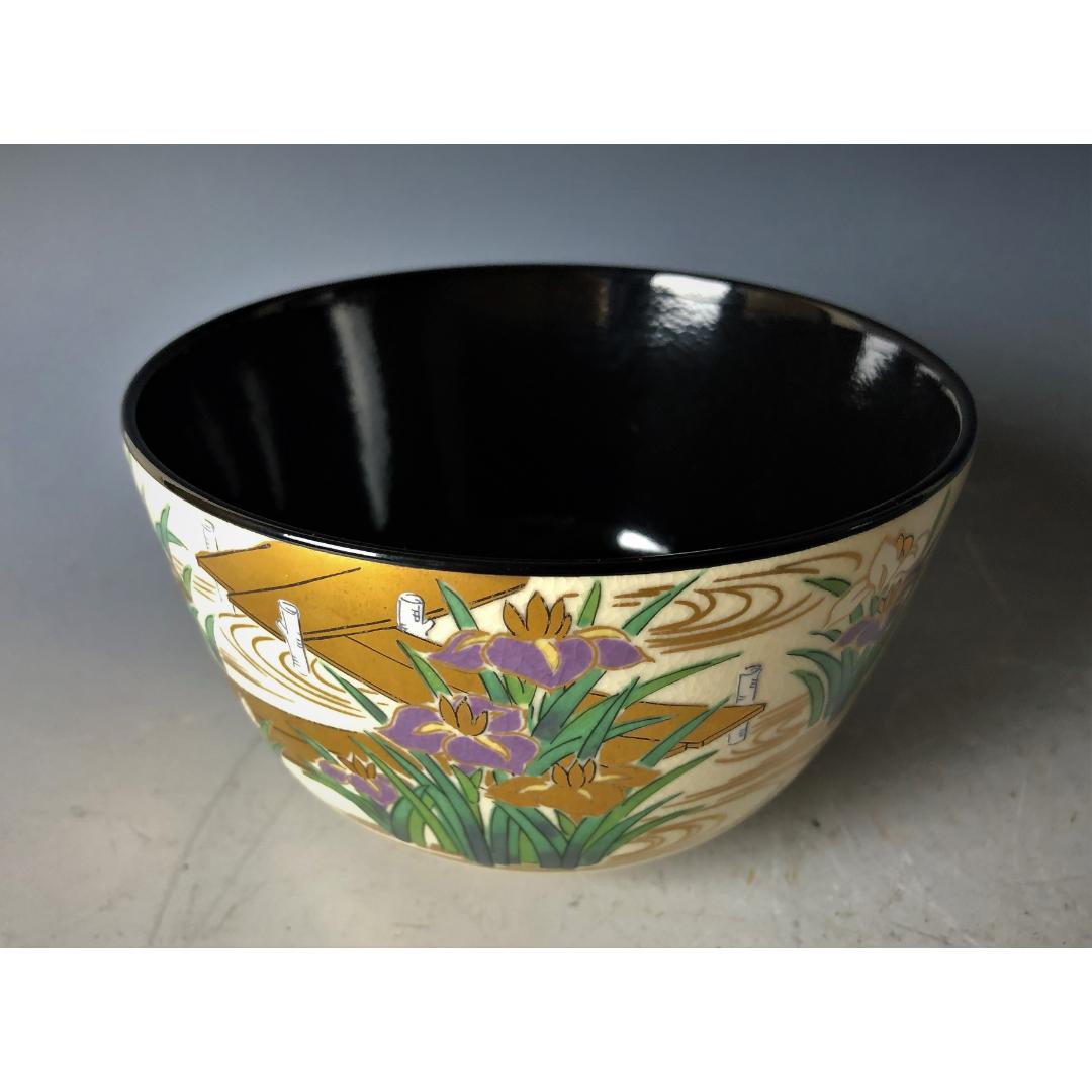  Elegantly crafted Kyo-yaki tea bowl with a glossy black interior transitioning to a hand-painted exterior featuring golden and purple irises on an ivory background.