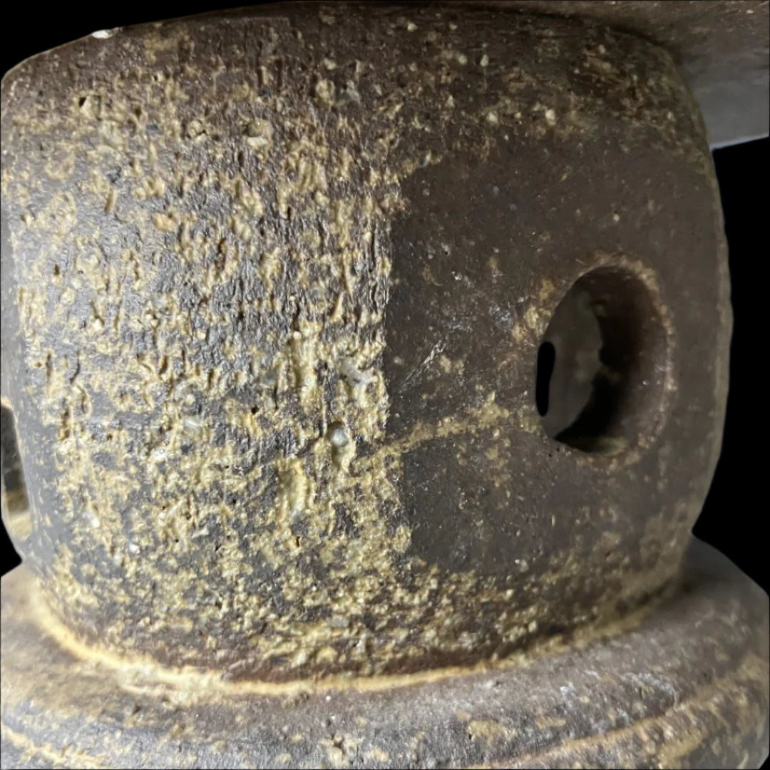 Close-up of a vintage Japanese stone lantern, showcasing a round cut-out detail and a textured weathered surface, emphasizing its traditional design and craftsmanship.