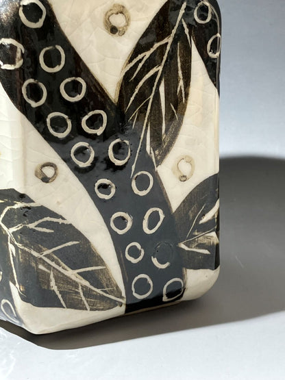 Ceramic tile with black and white leaf pattern on a gray background