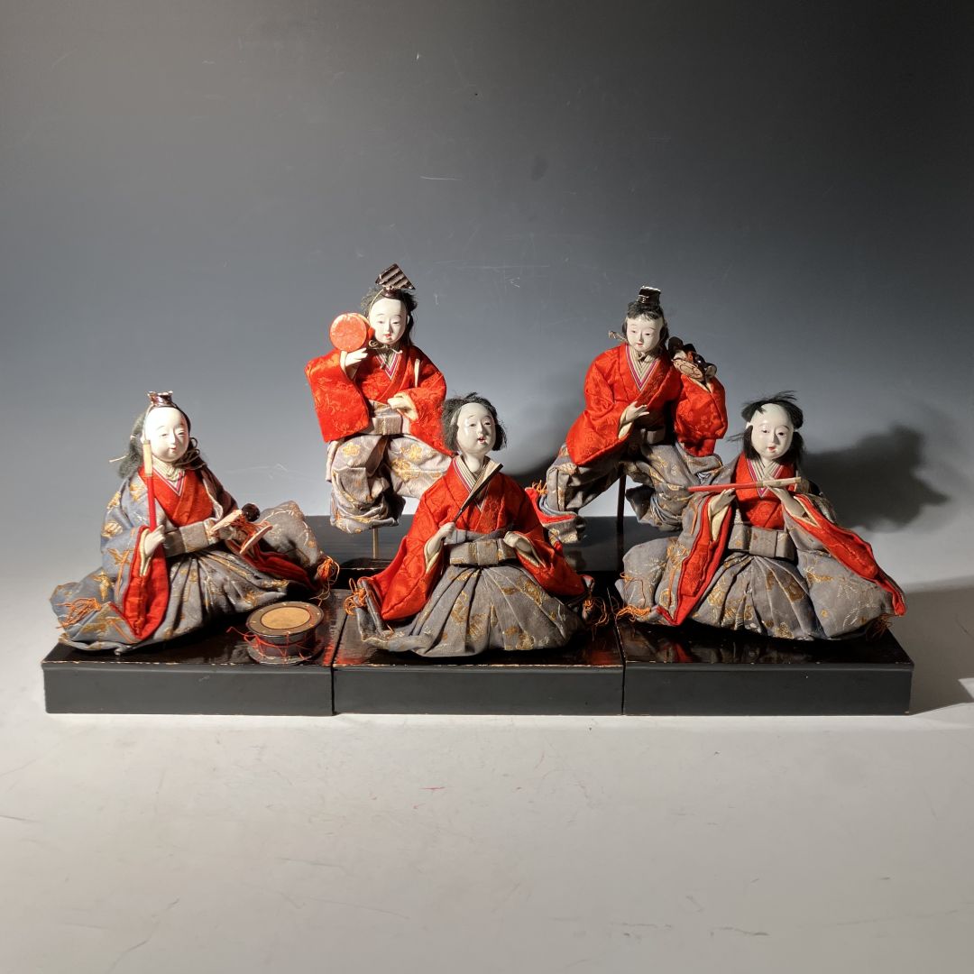 Set of six traditional Japanese figurines in red and gray attire on a dark base.