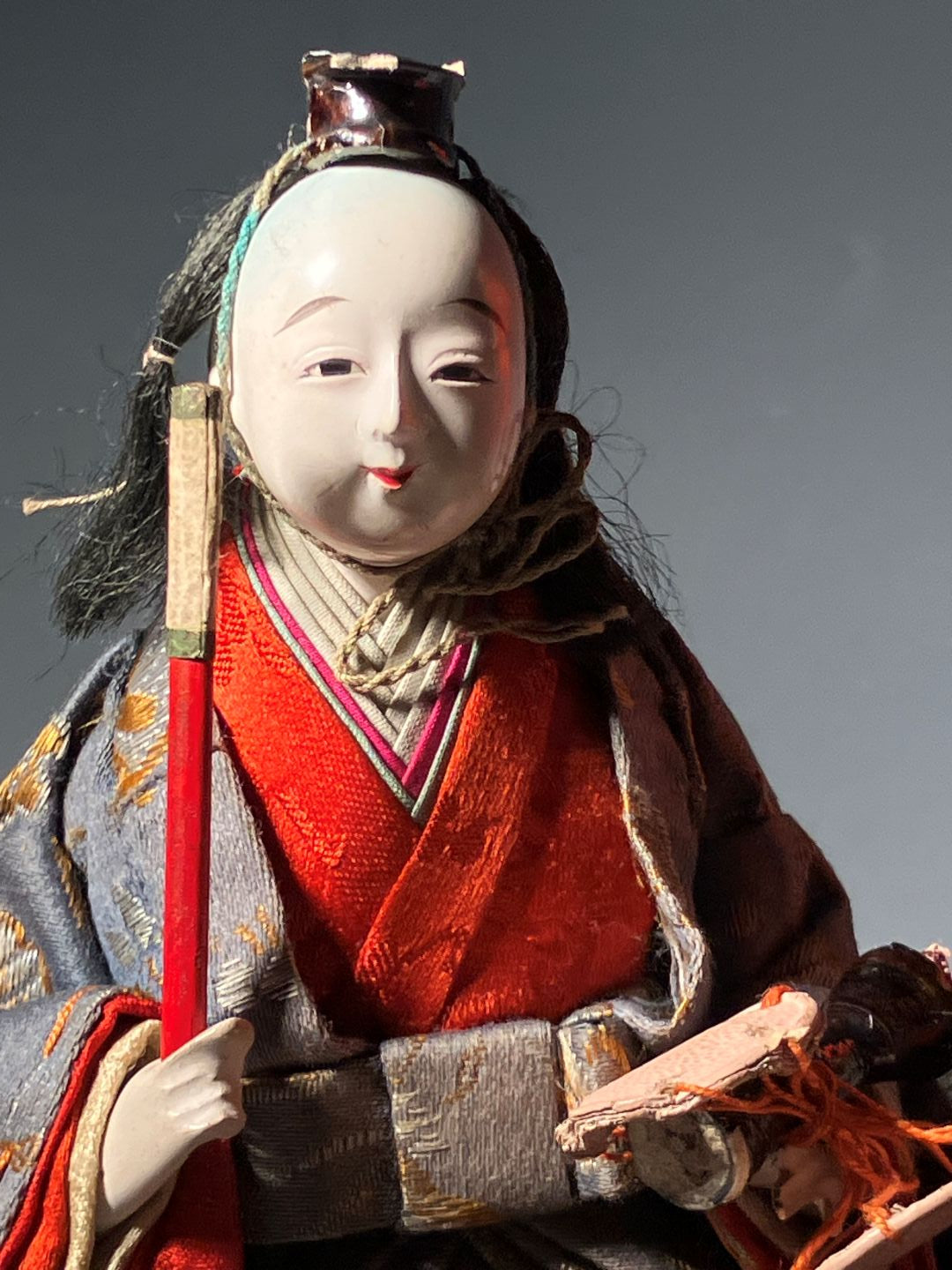 Traditional Japanese doll with intricate clothing and accessories on a dark background