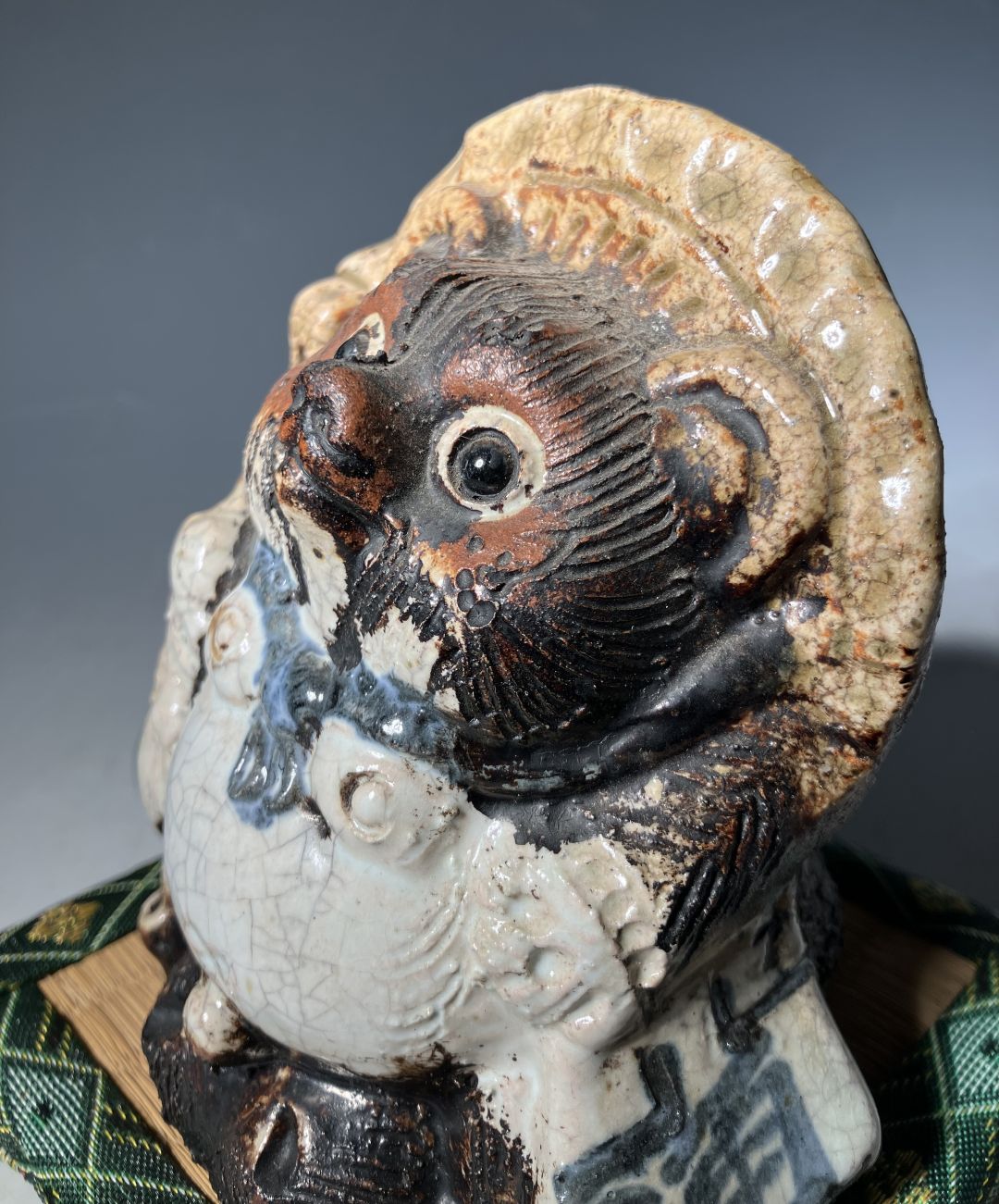 Ceramic sculpture of a stylized face with intricate details on a gray background