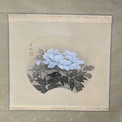 Framed artwork of a white flower with black leaves on a beige background
