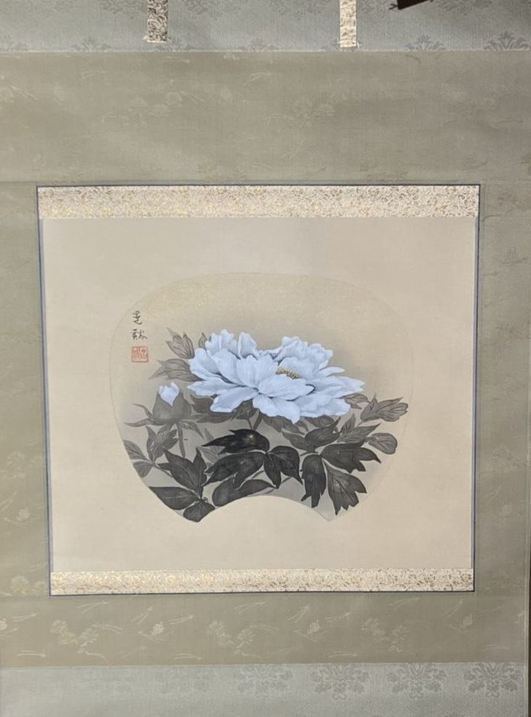 Framed artwork of a white flower with green leaves on a beige background