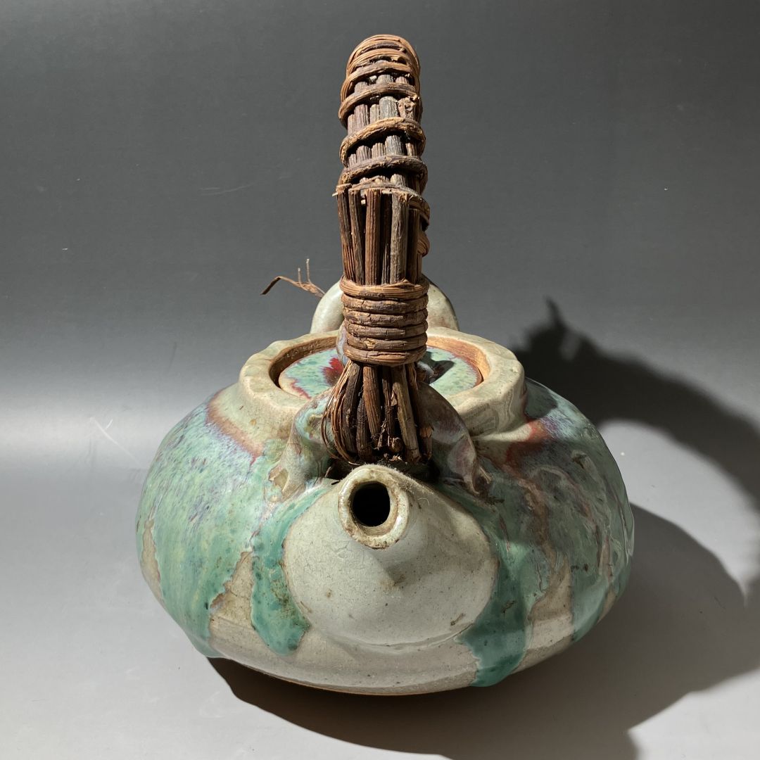 Ceramic oil lamp with woven wooden handle on a gray background