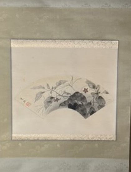 Framed artwork with a nature-themed design on a beige wall.