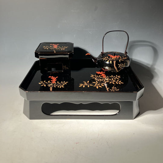 Black lacquerware set with floral designs on a gray background