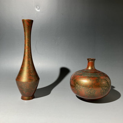 Two bronze vases with intricate designs on a gray background