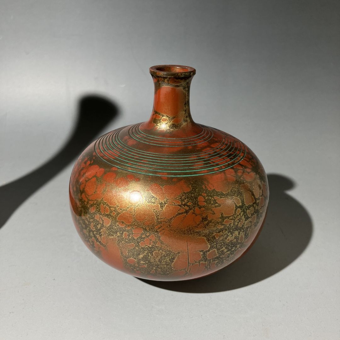 Decorative vase with red and gold patterns on a gray background