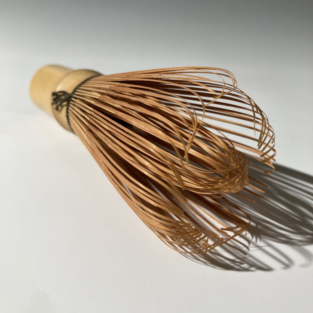 Traditional Japanese wooden tea whisk on a light background