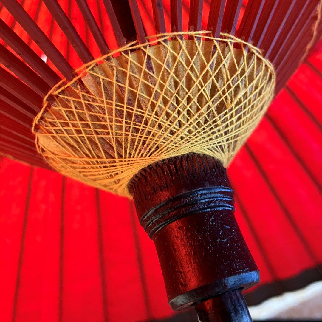 Close-up of a red umbrella with a wooden handle and yellow rib structure.