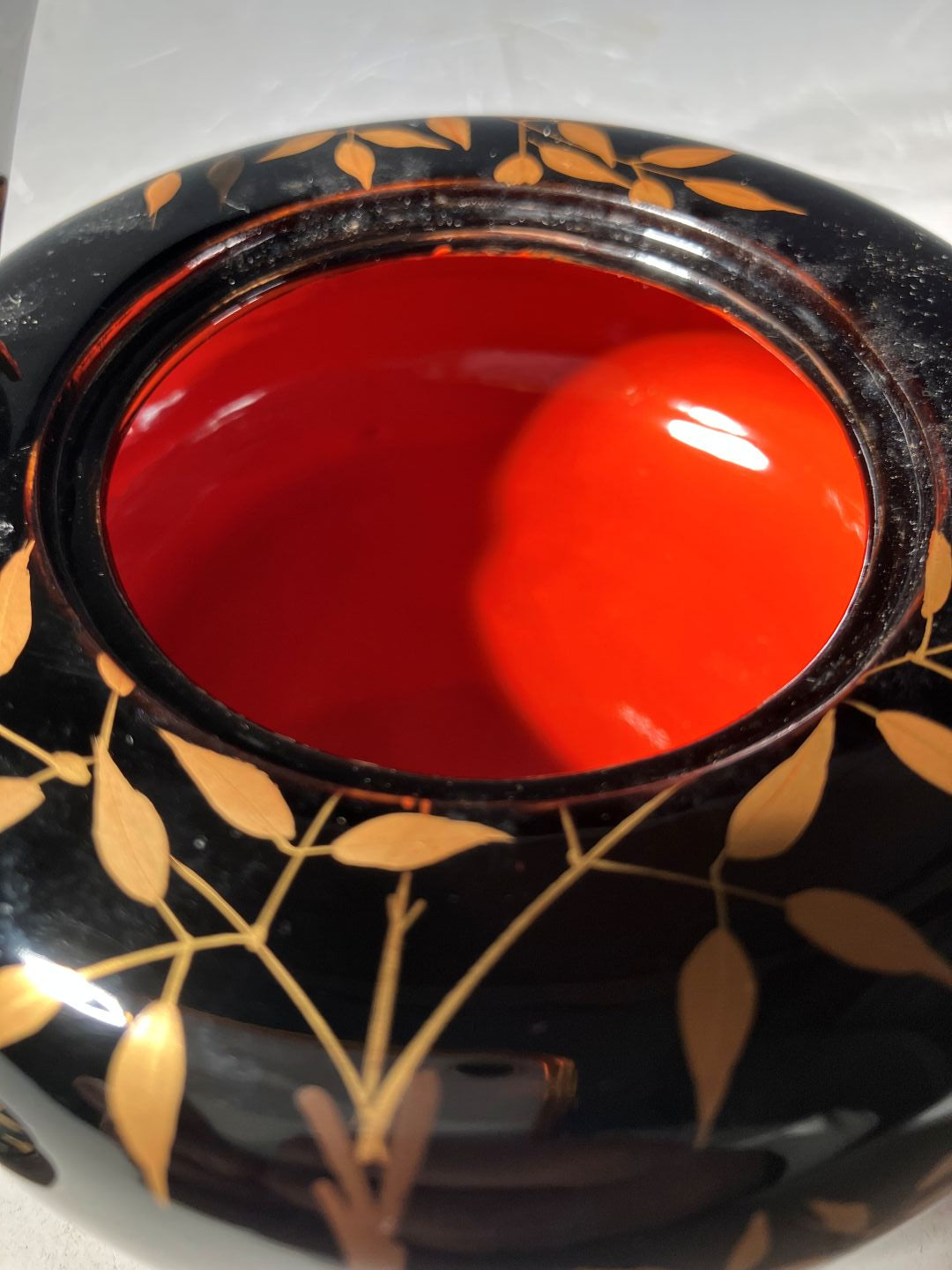 Decorative black bowl with gold leaf patterns and a red interior