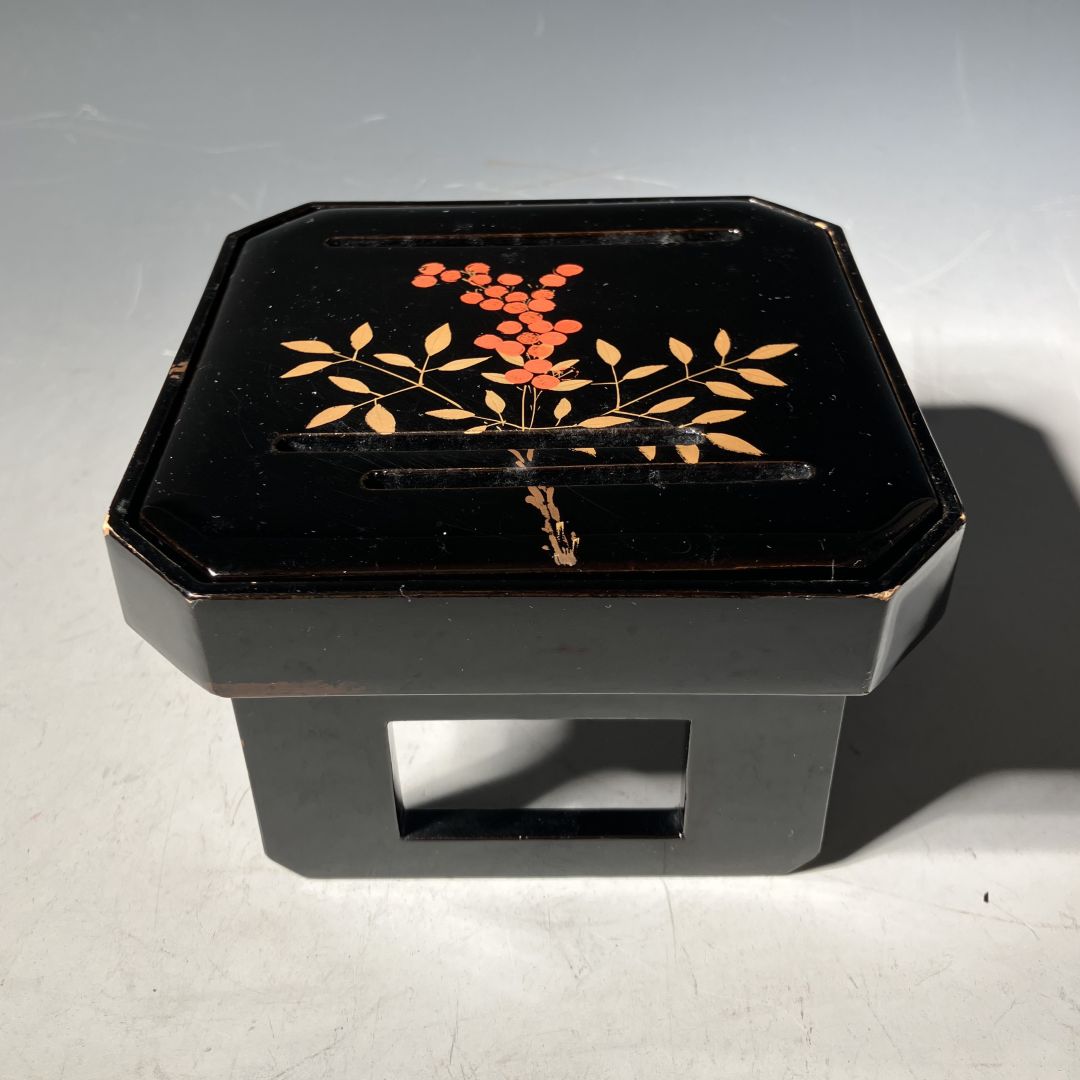 Black lacquerware box with floral design on a gray background
