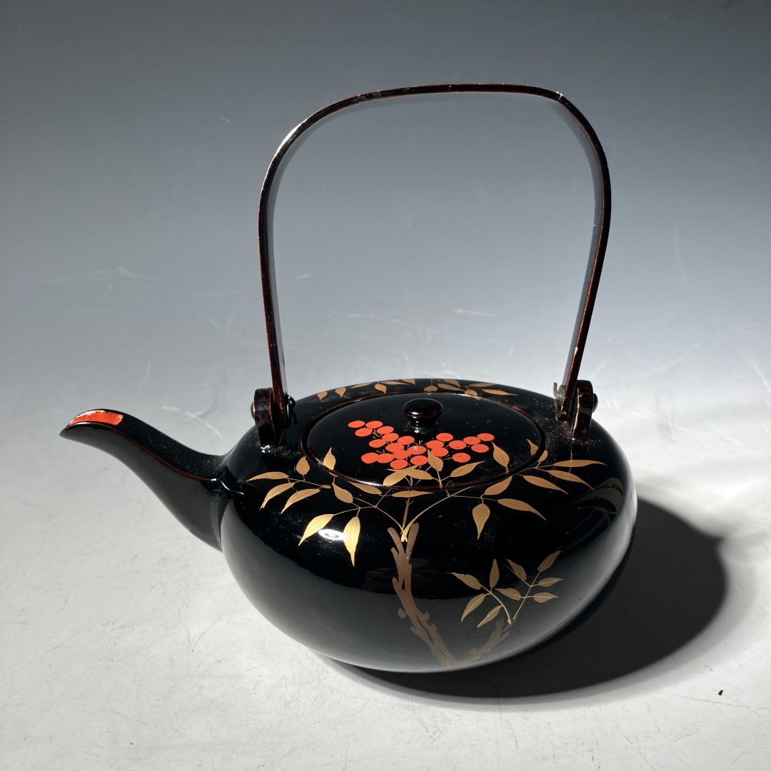 Black teapot with floral design on a gray background