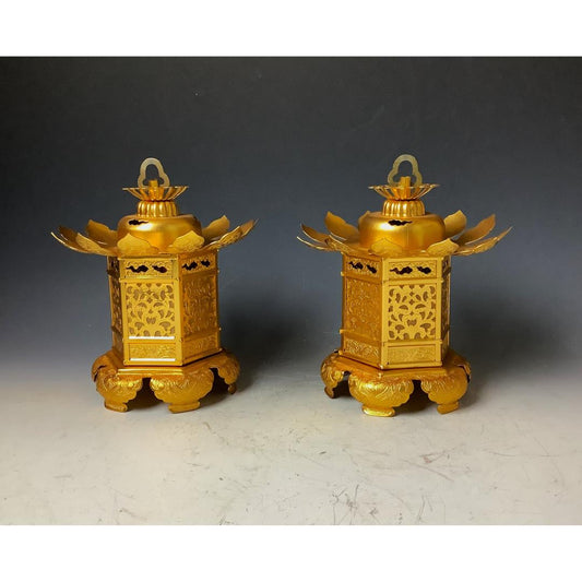 A pair of ornate golden Japanese lanterns with intricate cut-out designs and stylized bird wing accents, displayed on matching bases against a dark gray background.