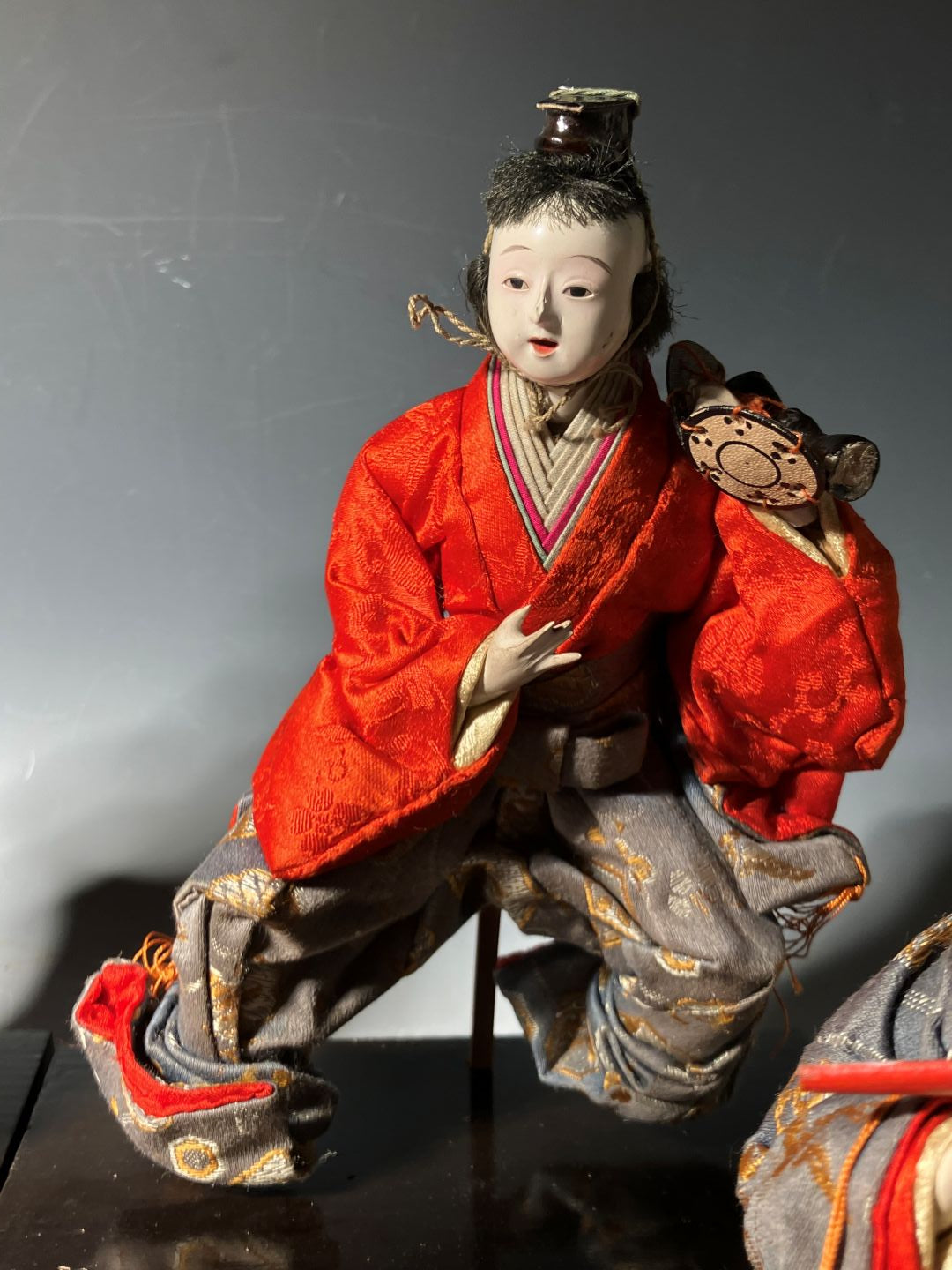 Traditional doll in red and black outfit on a reflective surface