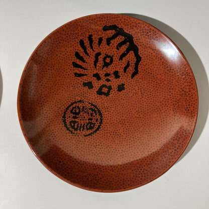 Brown ceramic plate with black textured design on a white background