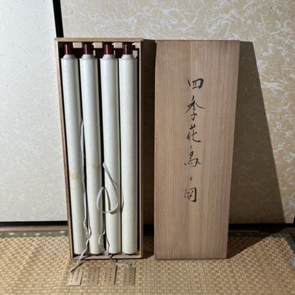 Wooden box with three cylindrical items inside, set against a textured wall.