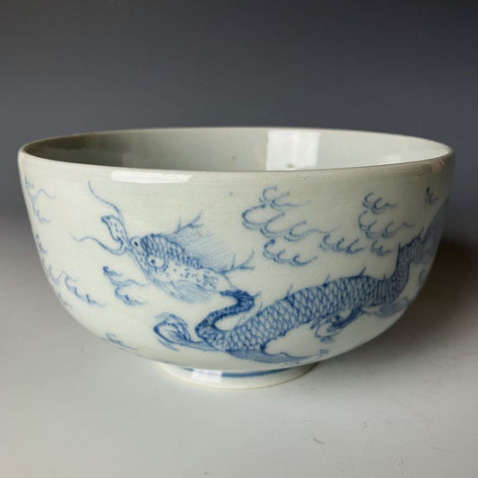 Antique Ko-Imari porcelain bowl with a blue hand-painted dragon and cloud design on a white background, showcasing traditional Japanese craftsmanship.