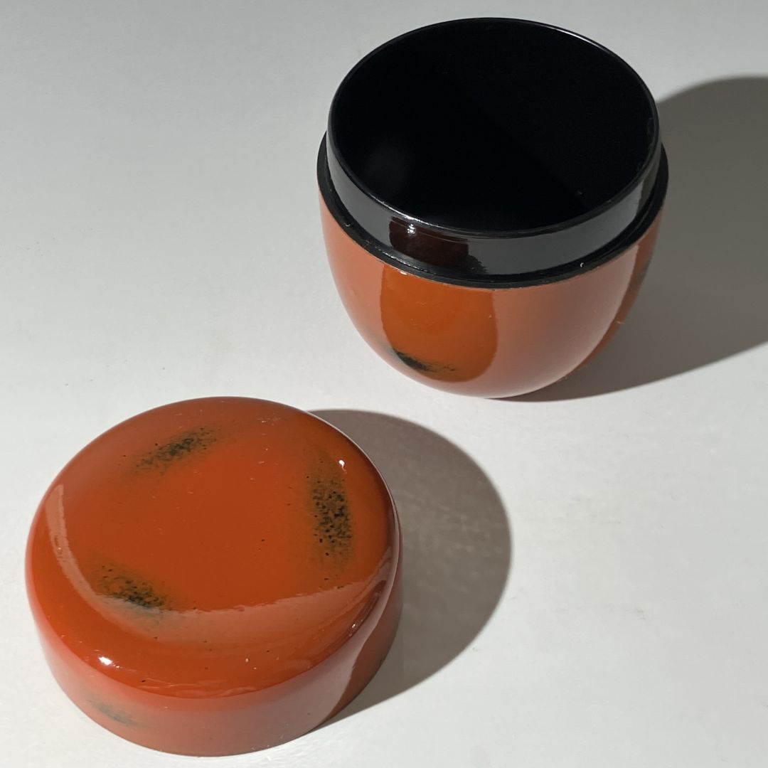 Two orange containers with black lids on a white background