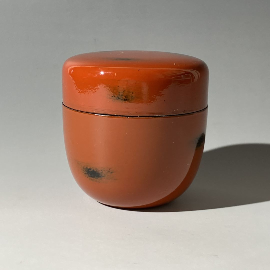 Small orange ceramic container with a lid on a gray background